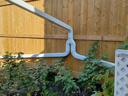 White downspout routed along a fence